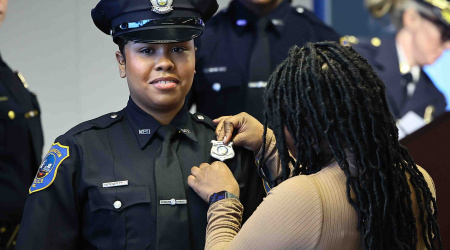 Cadet Destiny Snow-Ramos has her badge pinned by a family member during the 102nd Police Academy graduation